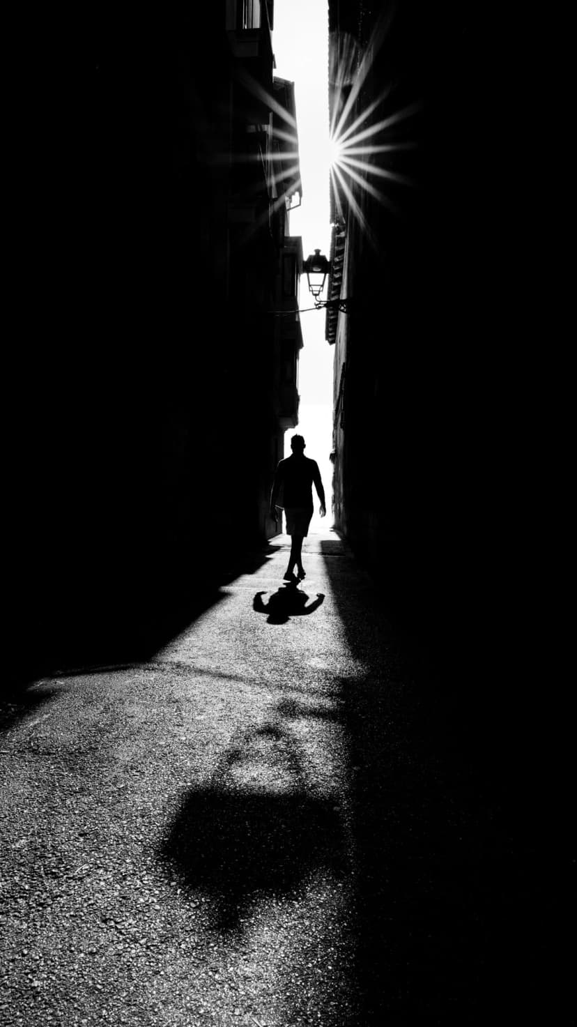 narrow light - figure mid-stride in sliver of light in palma old town alley