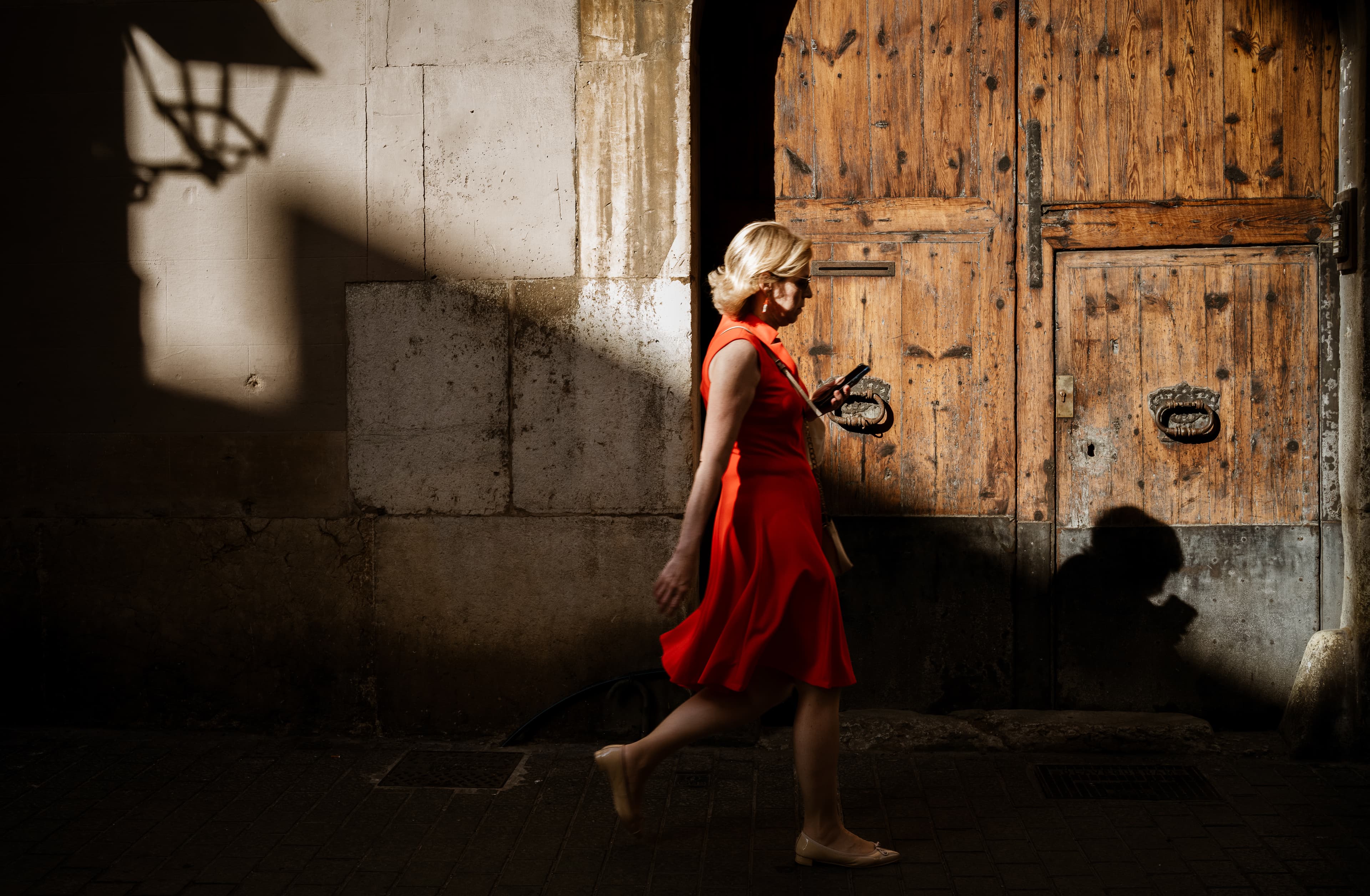 Woman in a red dress in front of weathered wooden doors, warm light