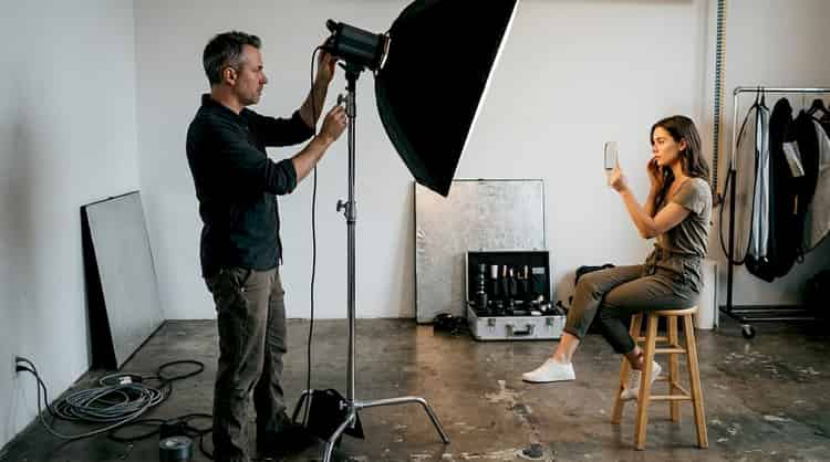 Photographer adjusting lighting for a studio portrait session